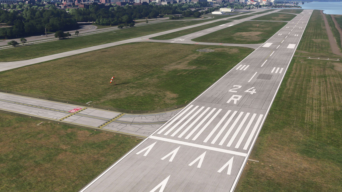 Aerial view along runway 24R at KBKL, showing threshold markings, taxiway connections, a windsock and the lakeside airfield in MSFS.