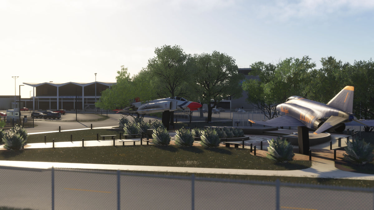 Aircraft monuments in U.S. Air Force and Blue Angels colors beside landscaped paths near the KBKL terminal in daylight in MSFS.