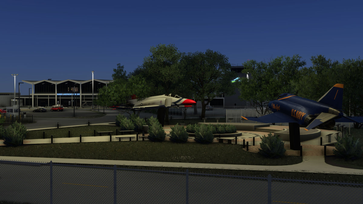 Aircraft monuments in U.S. Air Force and Blue Angels colors outside the illuminated KBKL terminal at night in MSFS.