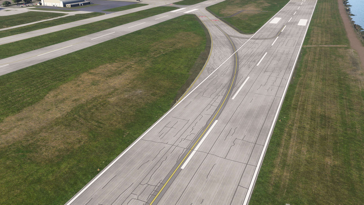 Aerial view of a KBKL runway exit with a curved yellow taxiway line, pavement crack detail and Lake Erie shoreline in MSFS.