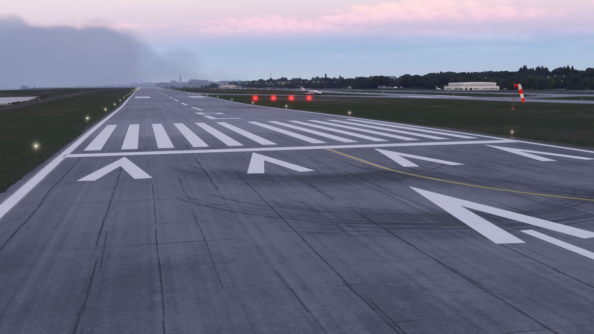 KBKL runway threshold at dusk with white markings, edge lights, red approach slope lights and a windsock in MSFS.