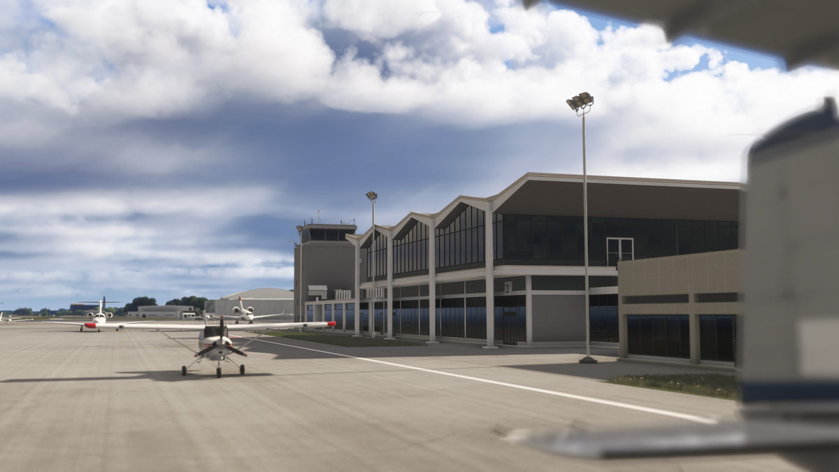 Close view of KBKL terminal windows, peaked roofline and control tower beside parked aircraft on the apron in MSFS.